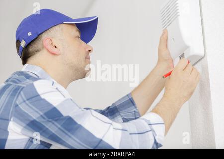 male technician installing alarm system indoors Stock Photo