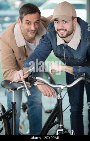 two bicycle repairer colleagues working in bike garage Stock Photo