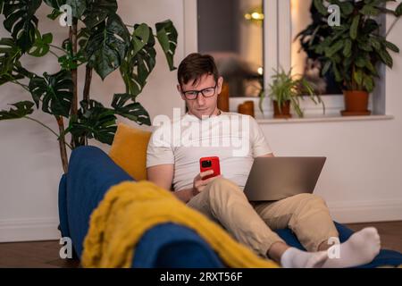 Man IT specialist working on laptop smartphone testing new programming apps Stock Photo