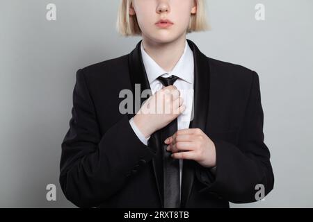 Woman putting on a tie on white background, closeup fashion portrait Stock Photo