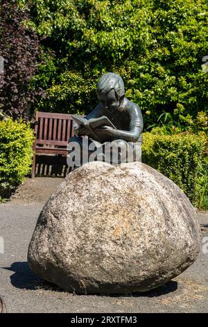 Peace and Tranquillity, Memorial Statue of a Boy Reading in The Secret Memorial Garden, Great Torrington, Devon, UK. Stock Photo