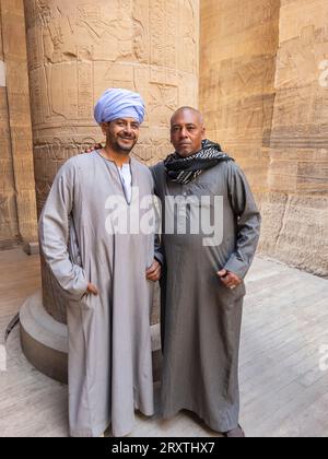 Two Egyptian men standing inside the Philae temple complex, The Temple of Isis, currently on the island of Agilkia, Egypt, North Africa, Africa Stock Photo