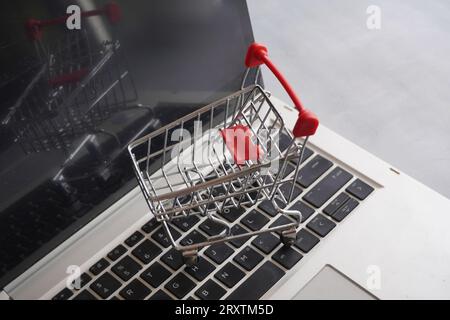 Closeup image of shopping trolley on top of laptop keyboard. Business and technology concept Stock Photo