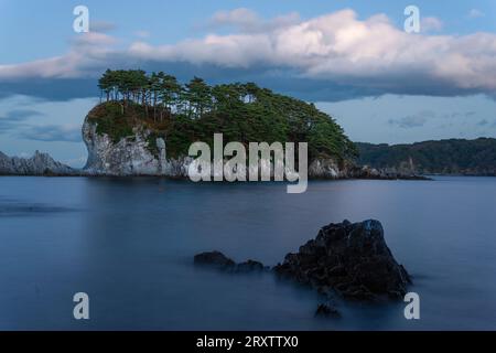 Long exposure of seascape with white cliff island with trees in distance, Jodogahama, Iwate prefecture, Japan, Asia Stock Photo