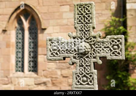 Anglo-Saxon Cross in the churchyard of St. Aidan's Church, a 12th century place of worship and a key location in the introduction of Christianity Stock Photo