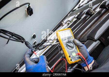 Solar panel on a roof being tested for its power output using a multimeter Stock Photo