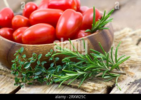mini roma tomatoes and herbs on wooden background Stock Photo - Alamy