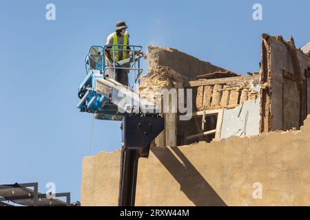 A worker demolish an old stone wall in Europe. Mid shot Stock Photo