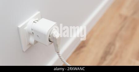 Using Wi-fi smart socket on the wall in a smart home, controlling electricity consumption Stock Photo