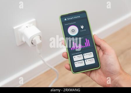 Using Wi-fi smart socket on the wall in a smart home, controlling electricity consumption Stock Photo