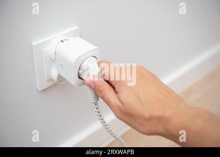 Using Wi-fi smart socket on the wall in a smart home, controlling electricity consumption Stock Photo