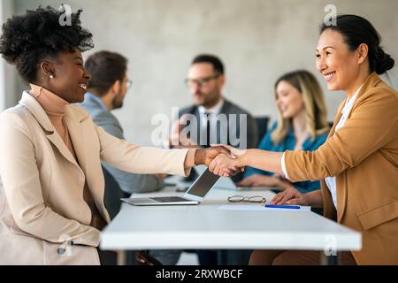 Business shaking hands, finishing up meeting. Successful businesswomen handshaking after good deal. Stock Photo