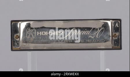 A metal and plastic harmonica used by Arthur Lee. The harmonica is etched with lettering on the top and bottom. The lettering on the top of the harmonica reads “HOHNER Special 20 / MARINE BAND.” The letter “A” is etched on the top right side of the harmonica. The etched lettering on the bottom of the harmonica reads “M. HOHNER / MADE IN GERMANY.” The harmonica has ten holes on each of its sides. Numbers are etched in the metal above each hole. Stock Photo