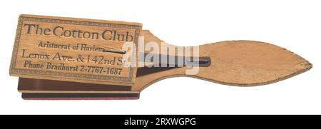 This is a wood clapper instrument with black etched type on front and back. Consisting of three pieces of wood, two small rectangles are attached via thin metal strips to the large paddle-shaped base, one on each side. There is black type on both small wooden rectangles. The type on one side of the clapper reads, 'The Cotton Club/ Aristocrat of Harlem/ Lenox Ave. & 142nd St. / Phone Bradhurst 2-7767-1687.' On reverse side type reads, 'Hear/ Ethel Waters/ Sing/ Stormy Weather/ Geo. Dewey Washington.' There is a decorative border in black ink around both rectangles. There is text on the reverse Stock Photo