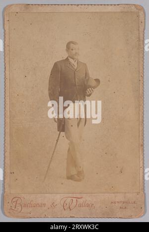 Photograph of a man in a suit, leaning on a cane and holding a hat late 19th century Stock Photo
