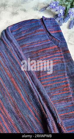 Handmade knitted products. Knitted cardigan made of purple and red threads. Gray background. Copy space Stock Photo