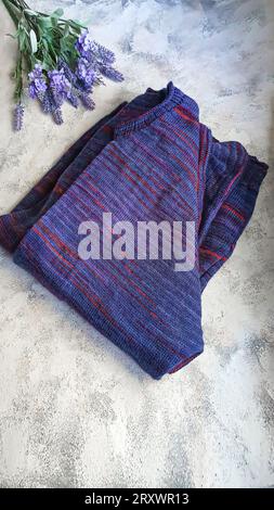 Handmade knitted products. Knitted cardigan made of purple and red threads. Gray background. Copy space Stock Photo