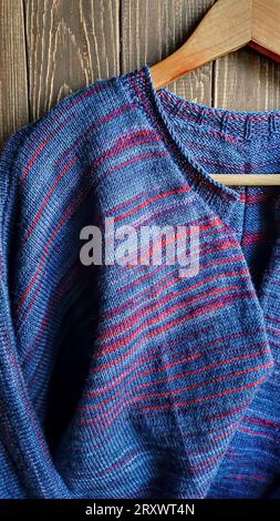 Handmade knitted products. Knitted cardigan made of purple and red threads. Gray background. Copy space Stock Photo