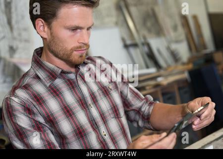 man measuring off metal bar in workshop Stock Photo