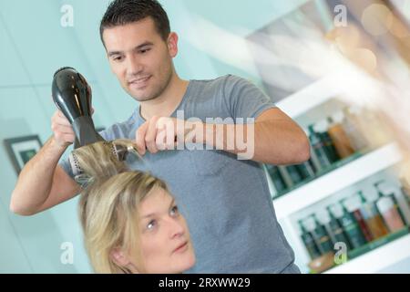 male hairdresser blow drying customers hair Stock Photo