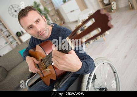 disabled man at home playing the guitar Stock Photo