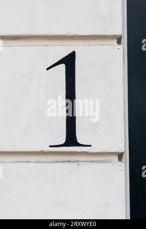 Number one door number hand painted in black on white wall Stock Photo