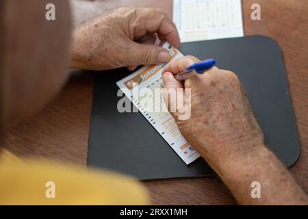 Goiânia, Goias, Brazil – September 26, 2023: Close-up on the hands of an elderly man who is marking the numbers on a lottery game card. Stock Photo