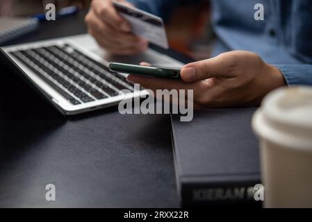 man hand holding a credit card and using a smartphone for online shopping. Stock Photo
