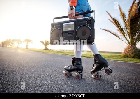 Woman, retro radio and outdoor with roller skates, music and training with freedom, road and summer. Girl, skating and vintage sound system for noise Stock Photo