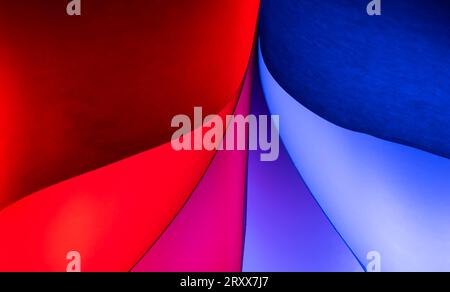 Closeup of red & blue colored curving shapes made for ordinary white sheets of paper and colored lights Stock Photo