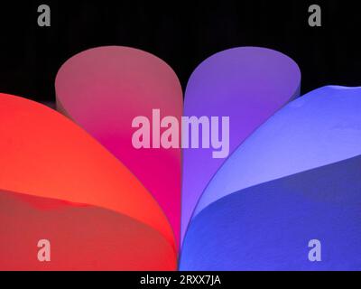 Closeup of red & blue colored curving shapes made for ordinary white sheets of paper and colored lights Stock Photo