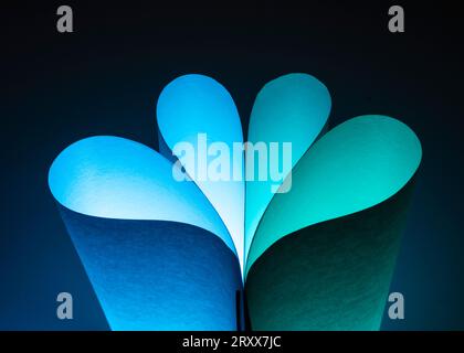 Closeup of green & blue colored curving shapes made for ordinary white sheets of paper and colored lights Stock Photo