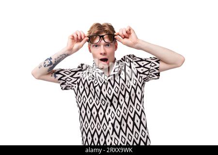 close-up of a young red-haired man in glasses with a tattoo on his arm trying to see the details in the distance Stock Photo