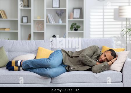 African american young man resting and sleeping on the couch at home after a hard day of work and study. Stock Photo