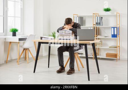 Exhausted worker tired of overworking sleeping on stacks of folders with documents in office. Stock Photo