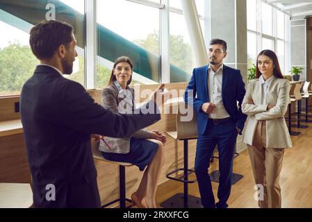 Business man speaking on meeting in office in front of a group of company employees. Stock Photo