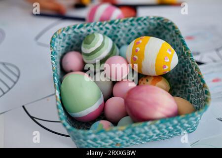 Close up of painted Easter eggs n tiny basket on table in arts and crafts class, copy space Stock Photo