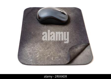 Computer mouse placed on an aged and well-worn mouse pad isolated on white background. Stock Photo