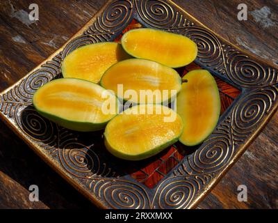 Mangos (Mangifera indica) in decorative fruit bowl, yellow flesh, wild mango, variety Emeraude Stock Photo