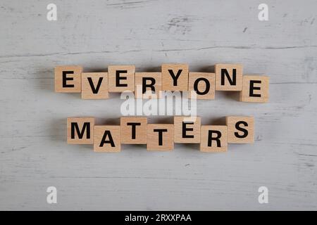 wooden blocks  in a white and grey board with the text everyone matters Stock Photo