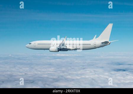 White passenger airliner flying in the air above the clouds Stock Photo