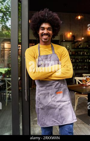 Young entrepreneur standing front of the camera and crossing arms smiling. Stock Photo