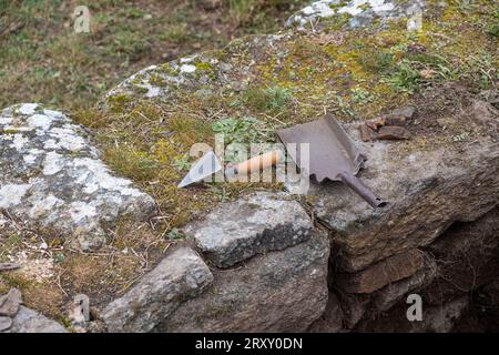 Tools of an archaeologist on a wall in an archaeological excavation, trowel and small shovel. Work tools Stock Photo