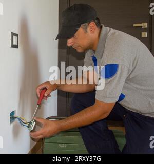 Image of a handyman electrician repairing and installing a home electrical outlet. DIY works power plug. Stock Photo