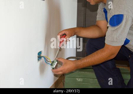 Image of a handyman electrician repairing and installing a home electrical outlet. DIY works power plug. Stock Photo