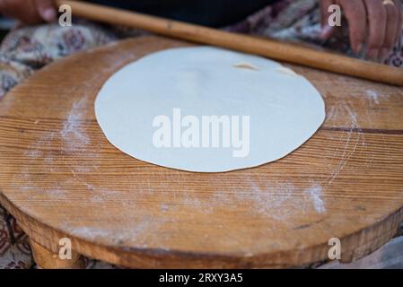 Rolling pin in woman hand rolling dough on traditional mini table , Preparing Gozleme is a traditional Turkish snack. High quality photo Stock Photo