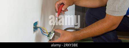 Image of a handyman electrician repairing and installing a home electrical outlet. DIY works power plug. Stock Photo