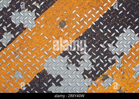 Yellow and black diagonal stripes on a houndstooth steel plate Stock Photo