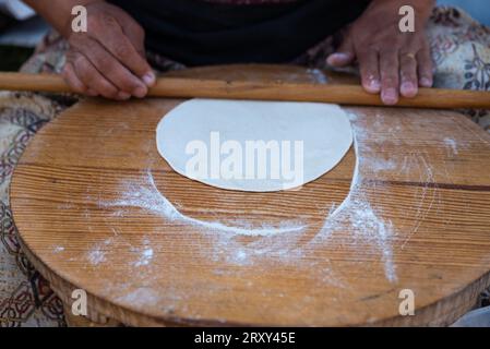 Rolling pin in woman hand rolling dough on traditional mini table , Preparing Gozleme is a traditional Turkish snack. High quality photo Stock Photo