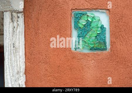 A figure 2 made from green coloured glass set into a rectangular panel on an orange painted exterior wall Stock Photo